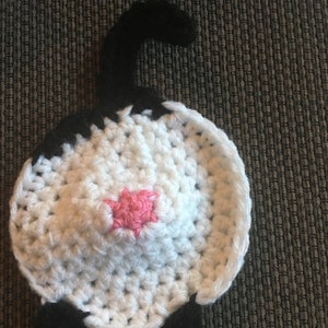 Puede incluir: Un gato de crochet blanco con orejas, cola y patas negras. El gato tiene una nariz rosa.