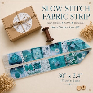 May include: A teal and blue slow stitch fabric strip, measuring 77 cm x 6 cm, with a variety of fabric patches, lace, and decorative elements. The text reads "SLOW STITCH FABRIC STRIP". A wooden spool and a small box are also present.
