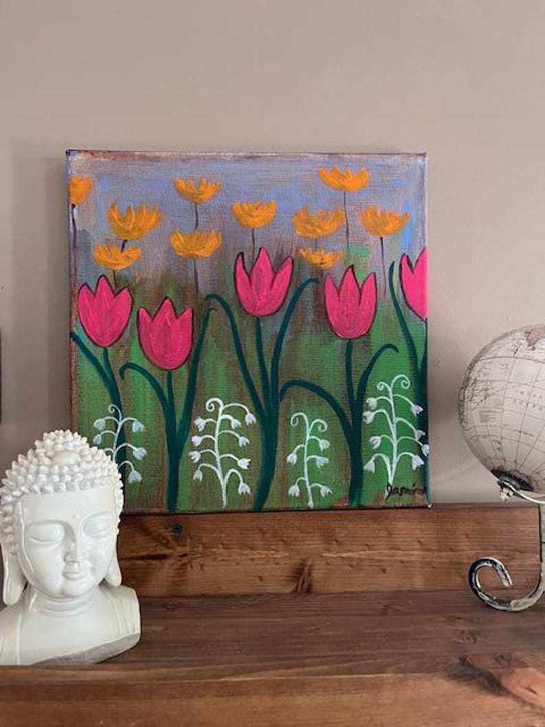 May include: A painting of a field of pink and yellow flowers. The flowers are painted in a stylized, whimsical style. The background is a light blue color. The painting is signed "Jamie".