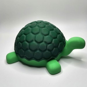 May include: A green 3D printed turtle toy with a textured shell. The shell is a darker green than the rest of the turtle.