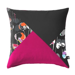 Peut inclure: Un oreiller noir et rose avec un motif floral. L'oreiller a un design géométrique avec un triangle noir, un triangle rose et une section noire avec un motif floral.