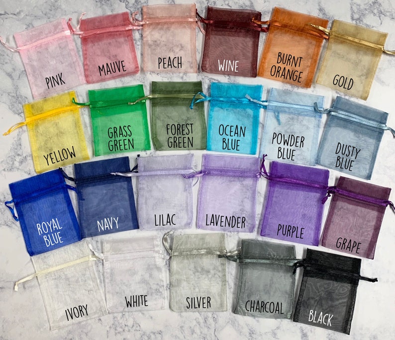 May include: A collection of 18 small, sheer fabric bags in various colors, including pink, mauve, peach, wine, yellow, green, blue, purple, gray, and white. Each bag has a label with a color name printed on it.