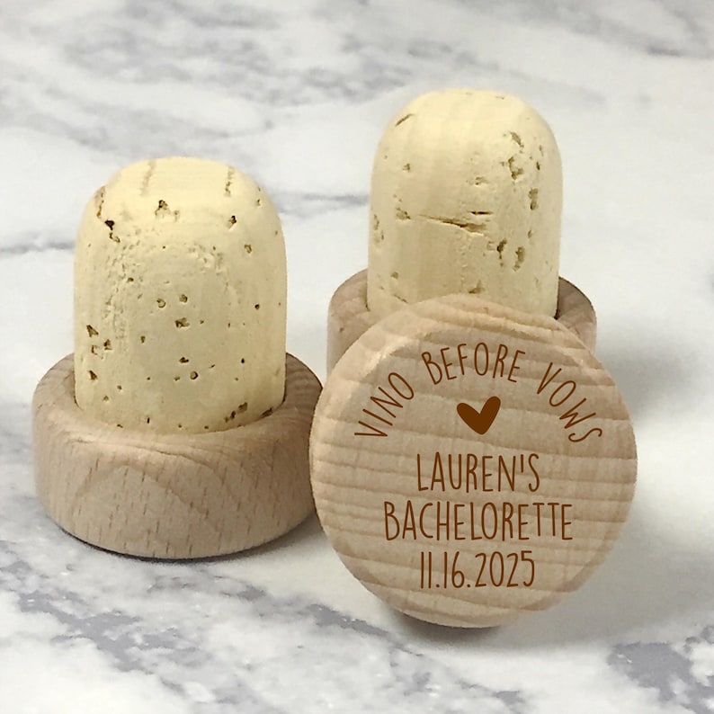 May include: Wooden wine bottle stoppers with a brown inscription that reads "Vino Before Vows Lauren's Bachelorette 11.16.2025" with a small heart symbol.