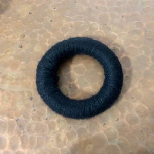 May include: A black yarn wreath, a simple and minimalist decoration.