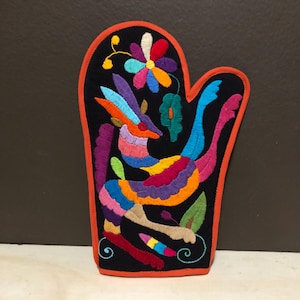 May include: A colorful embroidered oven mitt with a black background and an orange border. The mitt features a multi-colored animal design with a flower and leaves.