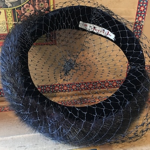 May include: A black velvet hat with a black net veil and a white label that reads "Jerri Jo".