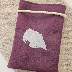 Puede incluir: Una bolsa de lino morado con cordón de ajuste y un contorno bordado blanco de un estado o región.
