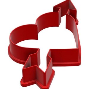 May include: A red plastic cookie cutter in the shape of a heart pierced by an arrow. The cutter has a thick, rounded edge and a simple, clean design, perfect for Valentine's Day or other romantic occasions.