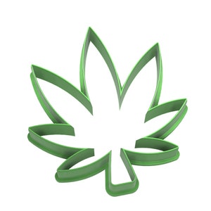 May include: A green, leaf-shaped cookie cutter with a cannabis leaf design. The cutter is made of a solid green material and has a smooth, rounded edge. The design is a stylized representation of a cannabis leaf.