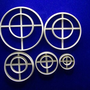 May include: A set of six white plastic circle cutters in varying sizes, arranged on a blue surface. Each cutter features a circular outer ring with a cross-shaped interior design. The sizes range from approximately 1 inch to 4 inches in diameter.