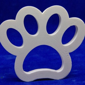 May include: A white, three-dimensional paw print cutout. The paw print has four oval toe pads and a larger, rounded heel pad. The object is made of a solid, textured material and is set against a blue background.