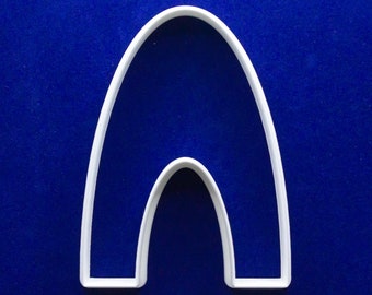 Puede incluir: Cortador de galletas de plástico blanco en forma de arco, con un arco más pequeño en el interior. El cortador está sobre un fondo azul liso. El diseño es simple y limpio, adecuado para hornear.