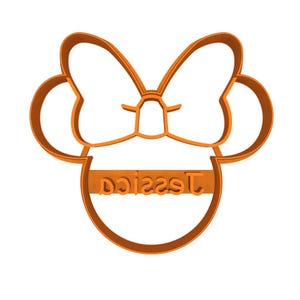 May include: An orange cookie cutter in the shape of a bow and mouse ears, with the name "Jessica" in a block font. The design is a single, continuous line, creating a simple, yet recognizable shape.