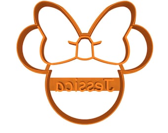 May include: An orange cookie cutter in the shape of a bow and mouse ears, with the name "Jessica" in a block font. The design is a single, continuous line, creating a simple, yet recognizable shape.