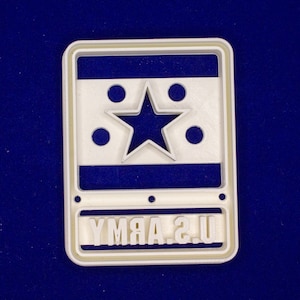 May include: A white rectangular object with a blue and white design, featuring a star in the center and the text "U.S. ARMY" at the bottom. The object has a light beige border and is set against a dark blue background.