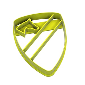May include: A yellow plastic cookie cutter shaped like a shield, featuring a horse head silhouette. The design includes a horse head in the upper left and two diagonal lines. The cutter is for baking.