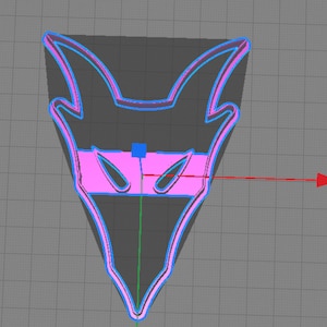 May include: A stylized, geometric design in the shape of a mask or emblem. The design features a dark gray outline with a light blue border and a pink interior. The shape has pointed ears and eye-like cutouts, with a horizontal pink band across the center.