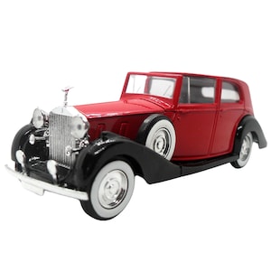 Könnte beinhalten: Ein rotes und schwarzes Oldtimer-Modell mit Weißwandreifen. Das Auto hat einen silbernen Kühlergrill, Scheinwerfer und einen Kühlerfigur. Der Oldtimer hat eine glänzende Oberfläche und steht vor weißem Hintergrund.