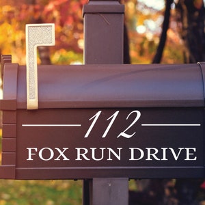 May include: A black mailbox with a white number "112" and the text "FOX RUN DRIVE" on the front. The mailbox has a gold-colored flag.