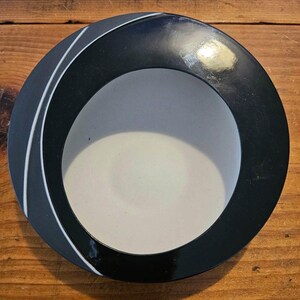 May include: A black and white ceramic bowl with a white interior and a black exterior. The bowl has a curved design with a white line running around the edge.