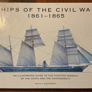 May include: A book titled "Ships of the Civil War 1861-1865" with an illustration of a tall ship with white sails and a small American flag. The book cover also includes the text "An Illustrated Guide to the Fighting Vessels of the Union and the Confederacy."