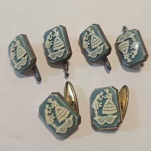 May include: Six blue and white cufflinks with a design of two figures in a romantic pose. The cufflinks have a gold-colored backing.