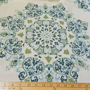 Peut inclure: Tissu crème avec un grand motif floral symétrique dans des tons de vert et de bleu sarcelle. Le motif comprend des volutes et des motifs de feuilles complexes. Une règle en bois avec des mesures en pouces est en bas.