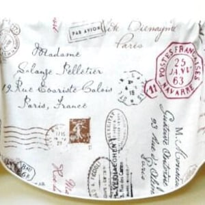 May include: Cream-colored valance with a vintage postal theme. Features stamps, handwritten script, and postmarks in brown and burgundy. The fabric is gathered at the top and has a scalloped bottom edge.