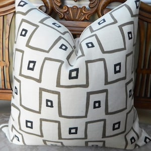 May include: Square decorative pillow with a geometric pattern. The pillow features a white background with a repeating pattern of gray squares and black square accents. The pillow is made of a textured fabric and is likely used for home decor.