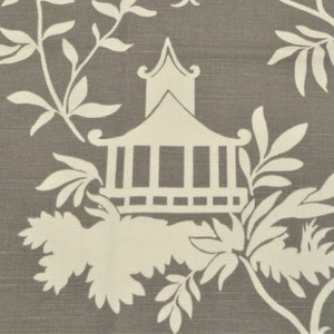 May include: Close-up of a fabric with a gray background and a white Chinoiserie design. The design features a pagoda, leaves, and branches. The fabric has a textured appearance.