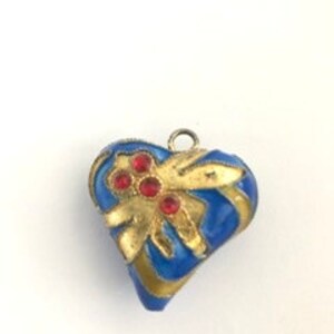 Op de afbeelding: Een blauwe en gouden hartvormige hanger met rode strass steentjes. De hanger heeft een gouden lus aan de bovenkant om aan een ketting te bevestigen.
