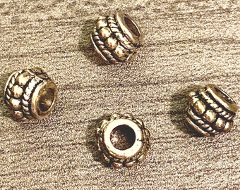 May include: Four silver-toned metal beads with a textured design. The beads have a round shape and a hole in the center.