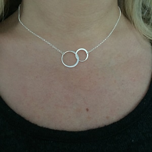 May include: A silver necklace with two interlocking circles as a pendant.