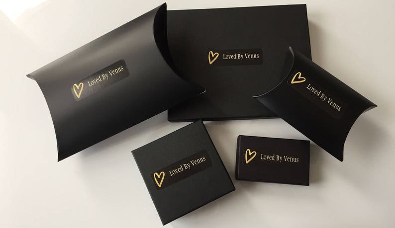 May include: Four black boxes with gold hearts and the text "Loved By Venus" on them. The boxes are different sizes and shapes.