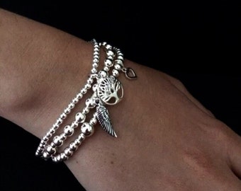 Set of 3 sterling silver stacking bracelets with tree of life, angel wing and heart charms. Silver stacking bracelet