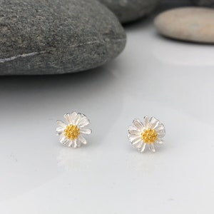 K&ouml;nnte beinhalten: Ein Paar silberne Daisy-Ohrstecker mit goldenen Zentren. Die Ohrringe sind klein und zart, perfekt f&uuml;r den Alltag.