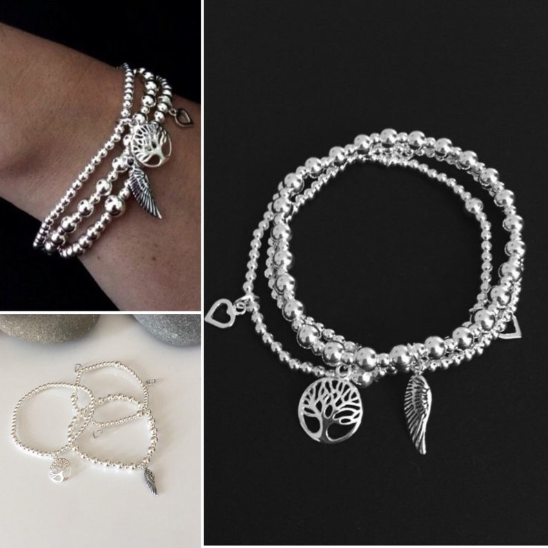May include: Three silver beaded bracelets with charms. The charms include a tree, a heart, and a wing.