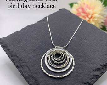May include: Sterling silver necklace with a pendant of seven interlocking circles. The circles are of varying sizes and have a textured finish.
