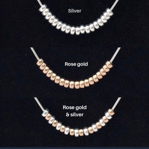 Three rows of beads with silver, rose gold, and a combination of rose gold and silver beads. The beads are displayed against a black background.