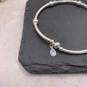 Puede incluir: Una pulsera de plata con un dije que dice "925". La pulsera tiene una serie de peque&ntilde;as cuentas de plata.