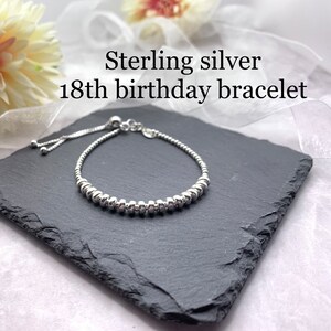 Sterling silver bracelet with a beaded design and an adjustable sliding clasp. The bracelet is on a black slate surface.