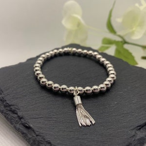 May include: A silver beaded bracelet with a silver tassel charm.