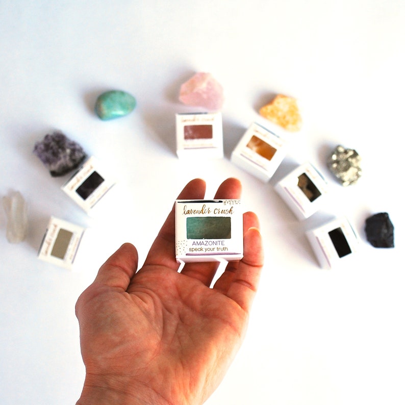 K&ouml;nnte beinhalten: Eine kleine, quadratische, wei&szlig;e Schachtel mit einem gr&uuml;nen Lidschatten darin. Die Schachtel tr&auml;gt den Text "lavende'r crush" und "AMAZONITE speak your truth".