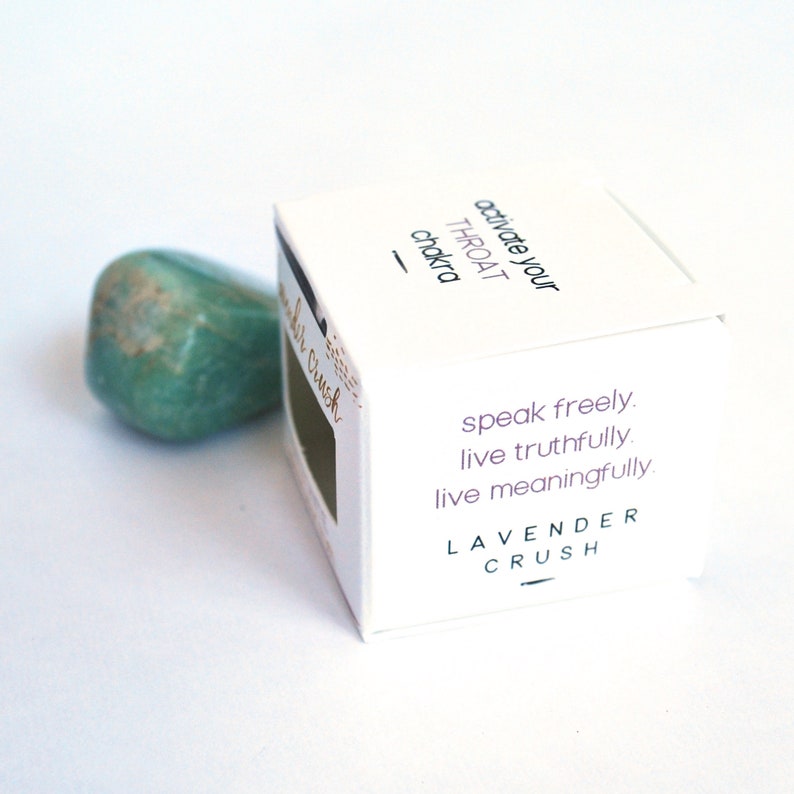 K&ouml;nnte beinhalten: Eine wei&szlig;e Box mit dem Text "activate your THROAT chakra" und "speak freely. live truthfully. live meaningfully." Die Box tr&auml;gt au&szlig;erdem den Schriftzug "LAVENDER CRUSH". Neben der Box liegt ein gr&uuml;ner Stein.