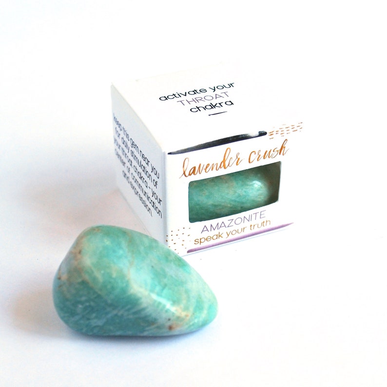 K&ouml;nnte beinhalten: Ein kleiner, gr&uuml;ner Amazonit-Kristall mit einer wei&szlig;en Schachtel, auf der "Aktiviere dein Kehlchakra" und "Lavender Crush" steht, sowie der Text "AMAZONITE speak your truth".