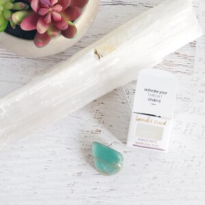 K&ouml;nnte beinhalten: Ein kleiner blaugr&uuml;ner Amazonit-Kristall mit einer wei&szlig;en Karte, auf der "Aktiviere dein Kehlchakra" und "Lavender Crush" steht, darunter der Text "Amazonit Sprich deine Wahrheit".