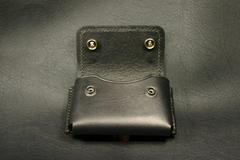 May include: A black leather wallet case with a flap closure and four brass rivets. The case is open and empty.