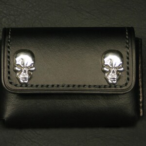 May include: Black leather wallet with two silver skull accents.