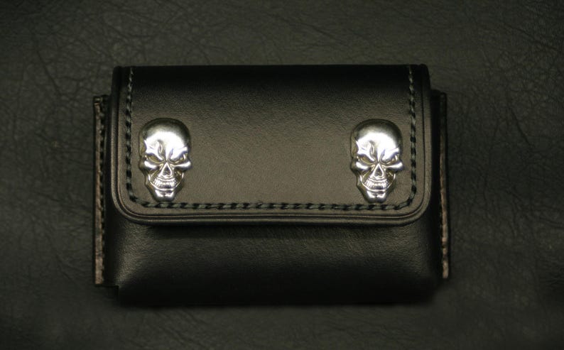 May include: Black leather wallet with two silver skull accents.