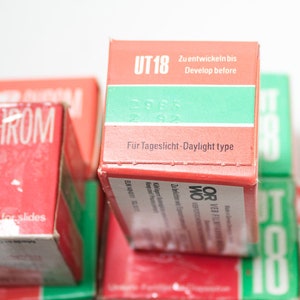 May include: A stack of red and green film boxes with the text "UT 18" and "ORWO CHROM" printed on them. The boxes are labeled "For Tageslicht - Daylight type" and "Zu entwickein bis - Develop before".